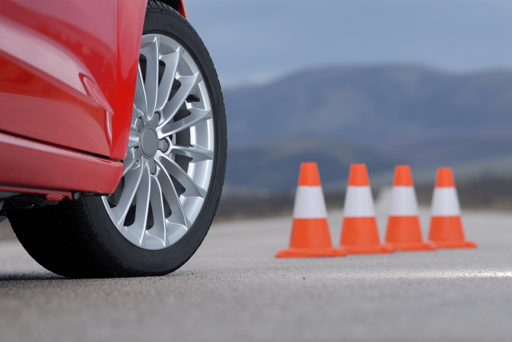 Close up of tire on red car and cones