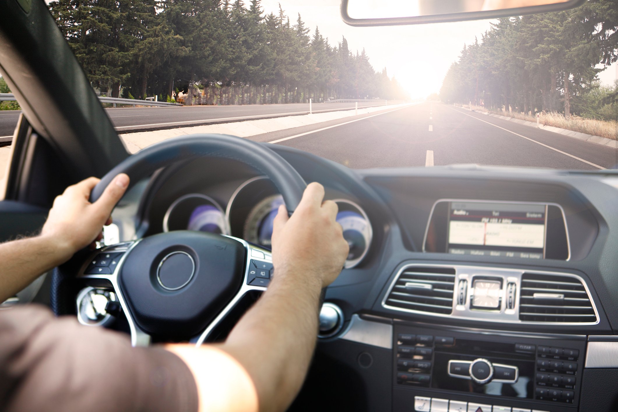 Person in short sleeve shirt with two hands on steering wheel