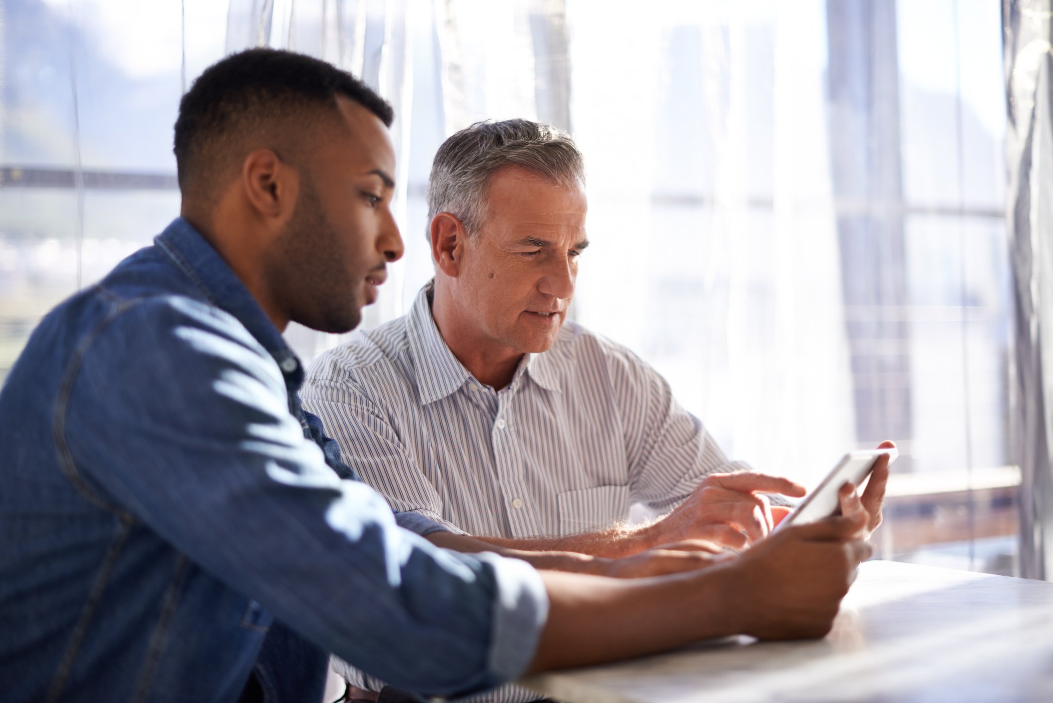 Two men looking at document on tablet