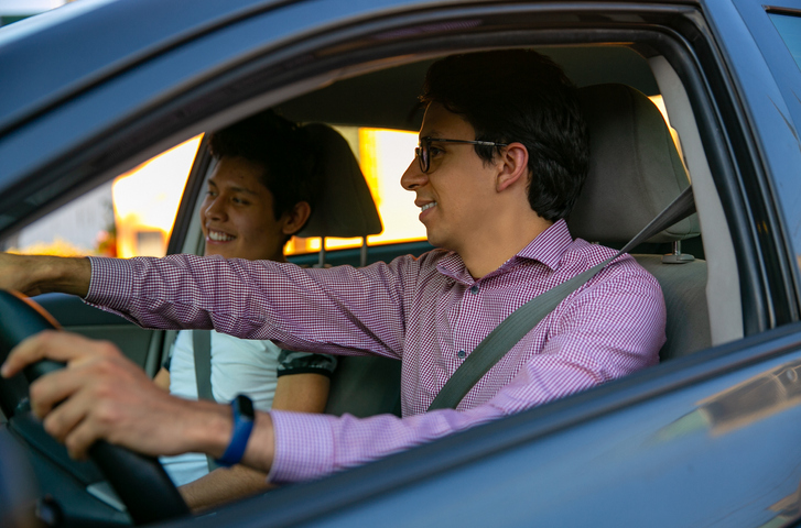 Father driving car with teem son in the passenger seat